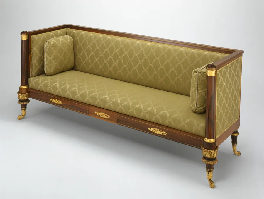 A long upholstered sofa with square arms level with its back, two cushions and short turned legs
