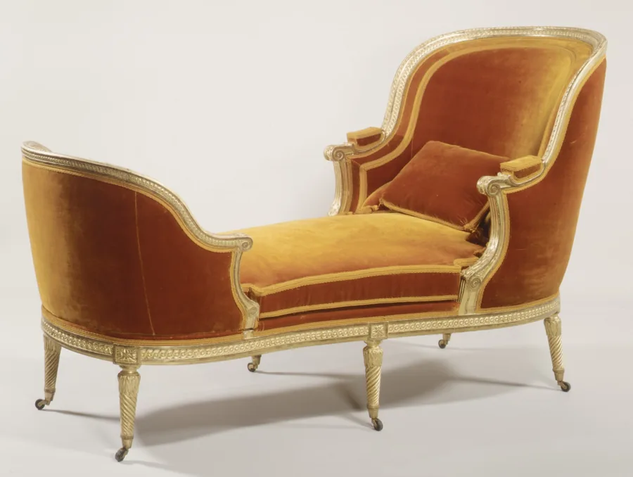 A gilded Louis XVI chaise longue in orange velvet with a high tub back, scroll arms and fluted legs