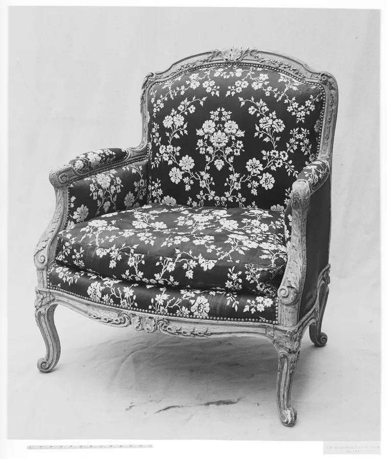 A Louis XV bergère armchair with floral upholstery, closed sides, a carved frame and cabriole legs