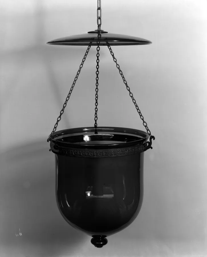 A dark glass bell lantern hanging on three chains below a round smoke bell
