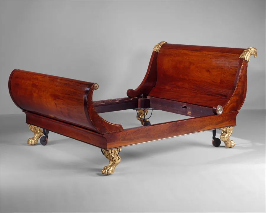 A mahogany sleigh bed with scrolled head and foot boards, gilt eagle heads and gilt paw feet