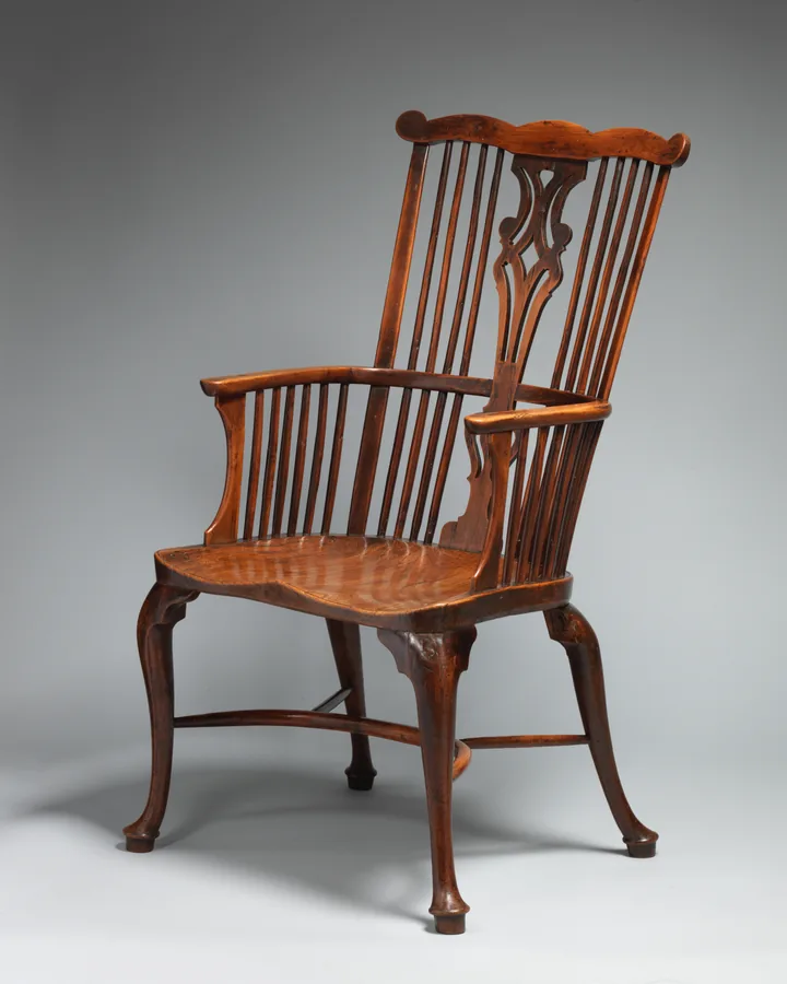An English yew-wood comb-back Windsor armchair with a pierced splat, spindles and cabriole legs