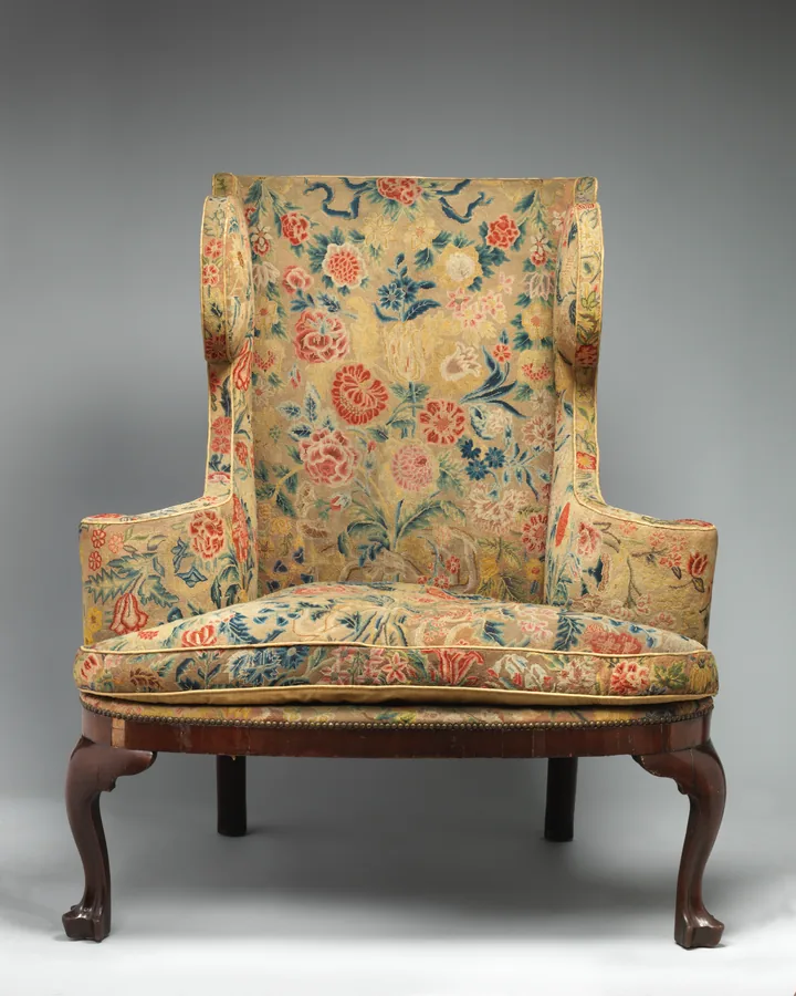 An English wing chair in floral needlework upholstery with rolled arms and cabriole legs