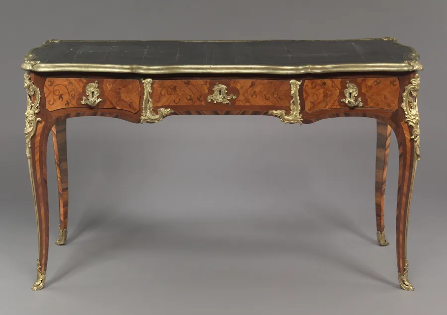 A Louis XV writing table with a leather top, marquetry drawers, gilt-bronze mounts and cabriole legs