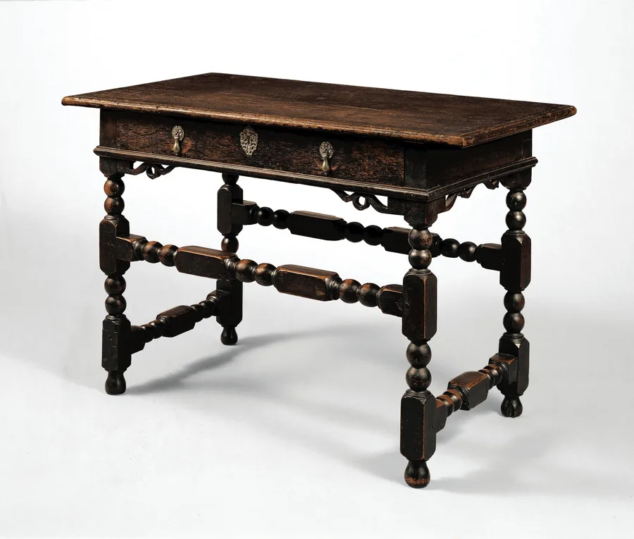 A dark oak and maple writing table with bobbin-turned legs and stretchers and one drawer with brass pulls